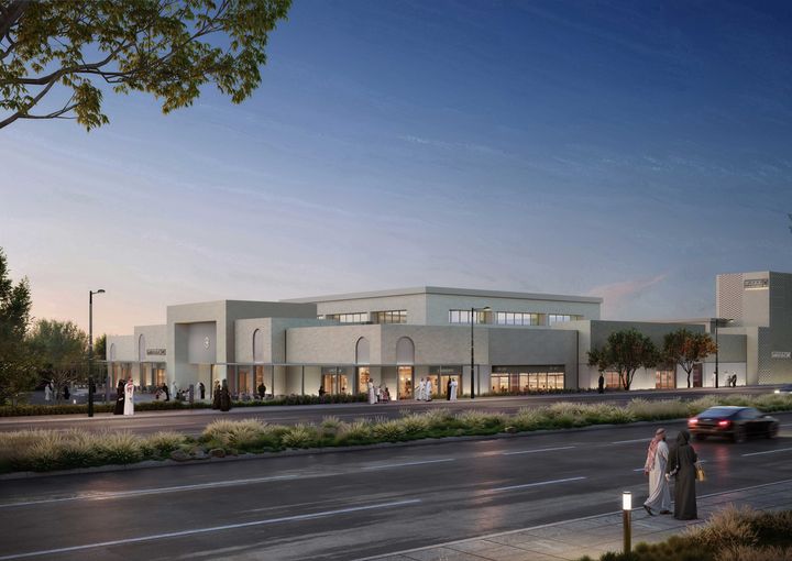 Architectural visualisation of Al Danah’s row of shops at dusk, with illuminated storefronts, pedestrians and a landscaped road.